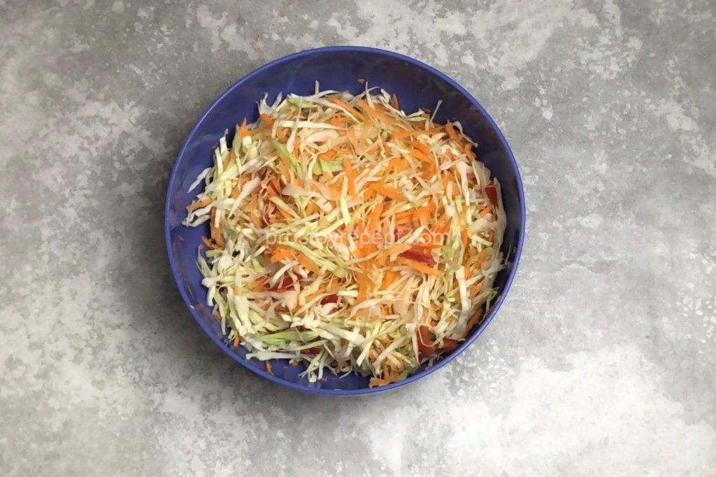Аккуратно смешайте капусту с нарезанными овощами, используя для удобства руки.