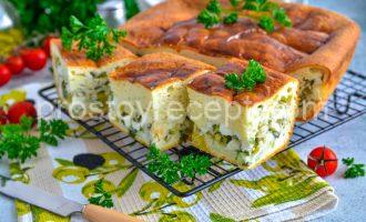 Аппетитный пирог с зеленым луком, нарезанный на порционные куски.